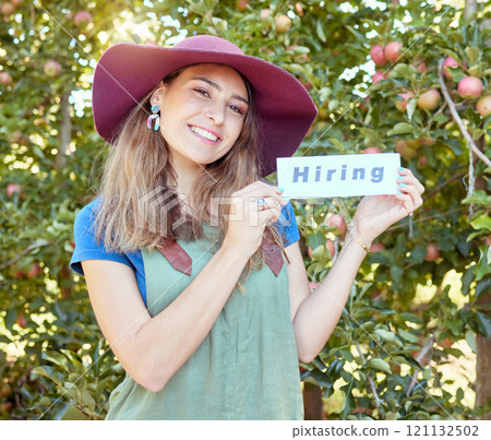Female apple farmer hiring workers to help on her fruit farm during harvest. Portrait of happy young woman advertising jobs and finding recruitment in an orchard on a sunny day near trees. 121132502