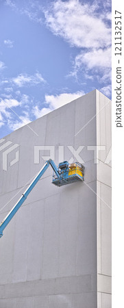 A hydraulic lift platform carrying boxes against grey wall building. Forklift or transport machinery used in construction and logistics industry for raising workers or as heavy duty freight elevators A hydraulic lift platform carrying boxes against grey wall building. Forklift or transport machinery used in construction and logistics industry for raising workers or as heavy duty freight elevators 121132517