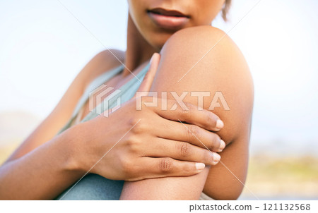 Female athlete suffering from shoulder pain while training outdoors. Fit woman holding her painful arm while exercising outside. Girl feeling her upper limb for an injury during a routine workout Female athlete suffering from shoulder pain while training outdoors. Fit woman holding her painful arm while exercising outside. Girl feeling her upper limb for an injury during a routine workout 121132568