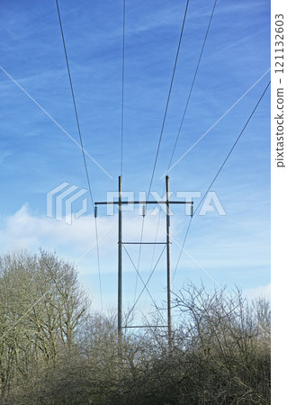 Power lines against clear blue sky background with copyspace. Industrial energy line, shut down for power cuts, roller power cuts. Controlling the energy crisis or preventing a total blackout Power lines against clear blue sky background with copyspace. Industrial energy line, shut down for power cuts, roller power cuts. Controlling the energy crisis or preventing a total blackout 121132603