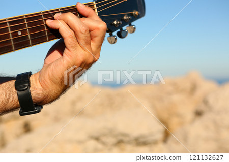 Close-up of a man playing the F chord on an acoustic guitar 121132627