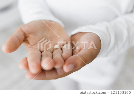 Small child hands holding baby tooth. Caucasian child, wearing white clothes, shows excitement about losing first teeth. Image embodies childhood milestones and growth. 121133160