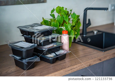 Black boxes with healthy diet plan for weight loss, delivery of daily ready meal menu. Food ordered with mobile phone app. Balanced portion with dish. Pre-cooking. Black boxes with healthy diet plan for weight loss, delivery of daily ready meal menu. Food ordered with mobile phone app. Balanced portion with dish. Pre-cooking. 121133736
