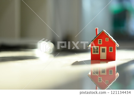 Small house model on floor, bathed in soft natural light. Real estate, investment and housing aspirations concept Small house model on floor, bathed in soft natural light. Real estate, investment and housing aspirations concept 121134434
