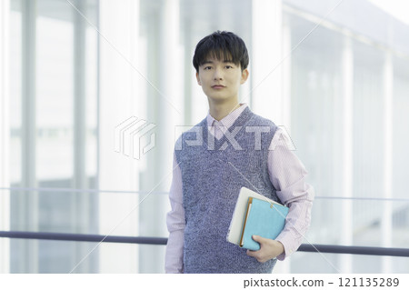 一個年輕人拿著筆記型電腦和筆記型電腦站著的肖像 121135289