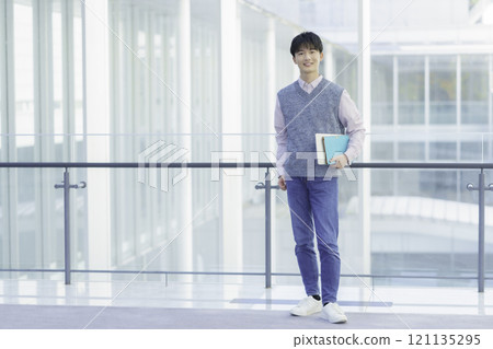 一個年輕人拿著筆記型電腦和筆記型電腦站著的肖像 121135295