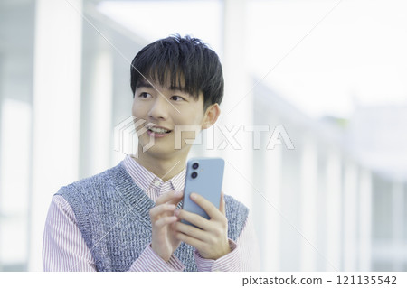 A young man operating a smartphone A young man operating a smartphone 121135542