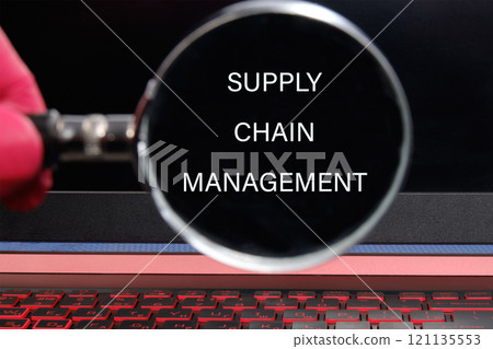 Business concept. SUPPLY CHAIN MANAGEMENT words through a magnifying glass on a black background Business concept. SUPPLY CHAIN MANAGEMENT words through a magnifying glass on a black background 121135553