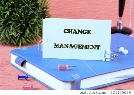 Business change management concept. Copy space. CHANGE MANAGEMENT words written on a white card standing on a business diary on an orange background 121135659