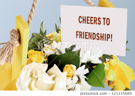 The conceptual phrase CHEERS TO FRIENDSHIP on a white card in a bouquet of flowers The conceptual phrase CHEERS TO FRIENDSHIP on a white card in a bouquet of flowers 121135660