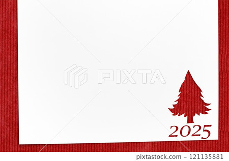 Christmas 2025 background. White paper with fir-tree shape cut for new year 2025 card on wooden table 121135881