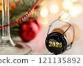 sparkling wine or champagne cork on table with christmas or new year 2025 blurred background and decorated fir-tree 121135892