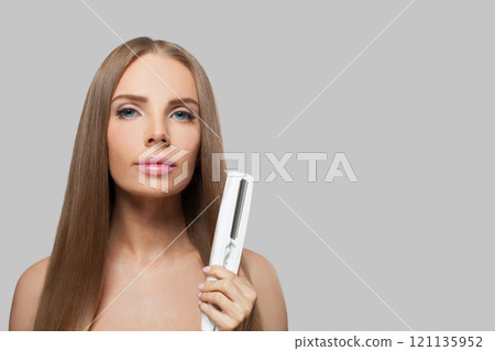 Glamorous woman with long hair using a straight hair iron and doing a hairstyle Glamorous woman with long hair using a straight hair iron and doing a hairstyle 121135952