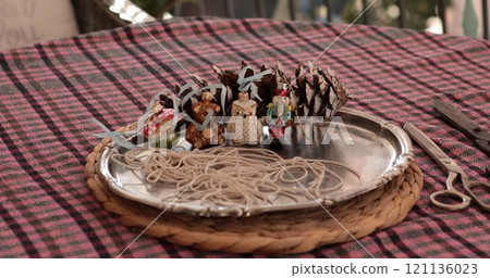 Sill life on vintage metal tray holding pinecones, decorative figures, and strands of string ready for a fun holiday craft project. This festive DIY activity brings joy to the season. 121136023