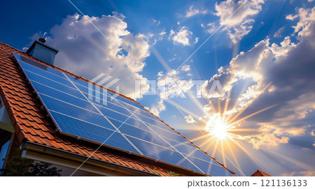 House roof with a solar panels on top, on a blue sky with clouds and sun rays. House roof with a solar panels on top, on a blue sky with clouds and sun rays. 121136133
