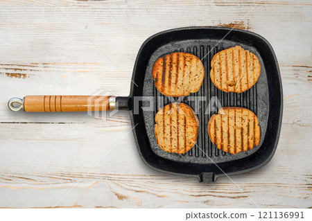 Top view of four slices of toasted bread in a griddle pan on a stovetop 121136991