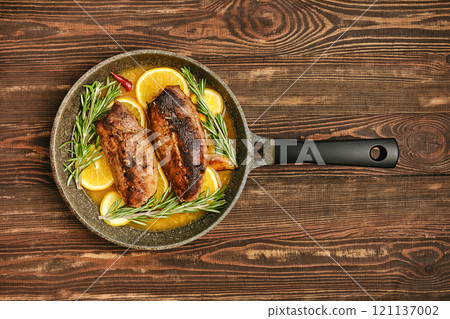 Grilled duck breasts with lemon and herbs in skillet on wooden surface Grilled duck breasts with lemon and herbs in skillet on wooden surface 121137002