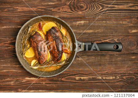 Savory roasted duck breasts with herbs and citrus in a frying pan 121137004