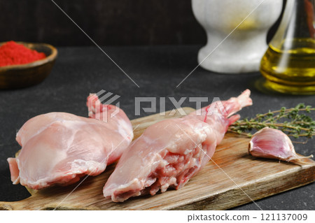 Fresh rabbit meat on a wooden cutting board with herbs and spices in the kitchen Fresh rabbit meat on a wooden cutting board with herbs and spices in the kitchen 121137009