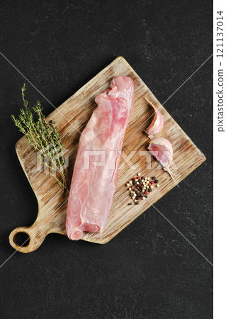 Raw rabbit tenderloin prepared with garlic and thyme on a wooden cutting board 121137014