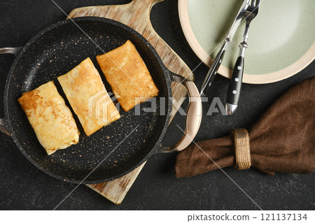 Delicious freshly cooked crepes served in a frying pan with cutlery and a napkin Delicious freshly cooked crepes served in a frying pan with cutlery and a napkin 121137134
