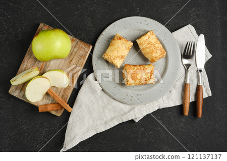 Delicious apple-filled crepes served with fresh fruit and cinnamon on a rustic table 121137137