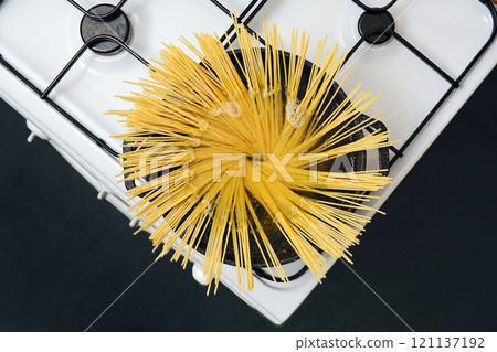 Cooking spaghetti in a pot filled with boiling water on a stove at home kitchen 121137192