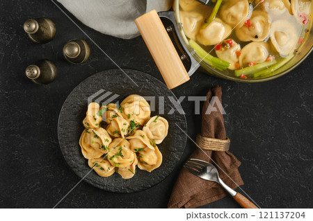 Dumplings served on a plate with broth and garnishments in a kitchen setting 121137204