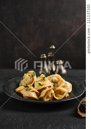 Delicious dumplings served on a dark stone plate with spices in background 121137205