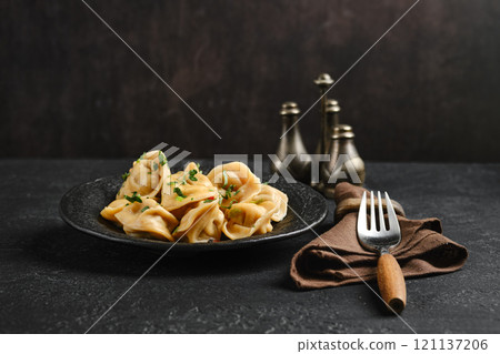 Delicious dumplings served on a dark plate with herbs and spices in a cozy dining setup 121137206