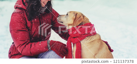 Young happy girl with a Labrador retriever dog are best friends. The girl and dog are outdoors in winter 121137378