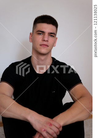 young casual man sitting with legs crossed and holding his head while smiling to the camera. isolated on white 121138025