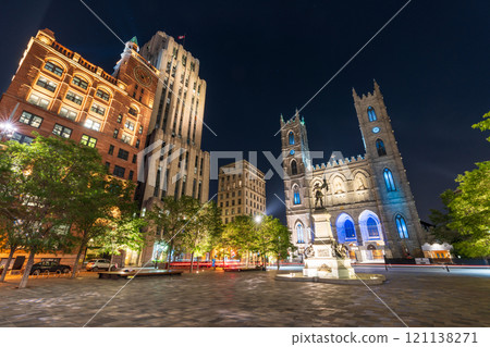 Montreal, Quebec, Canada - August 18 2021 : Night view of Place d'Armes in Old Montreal. Notre-Dame Basilica. Maisonneuve Monument. 121138271