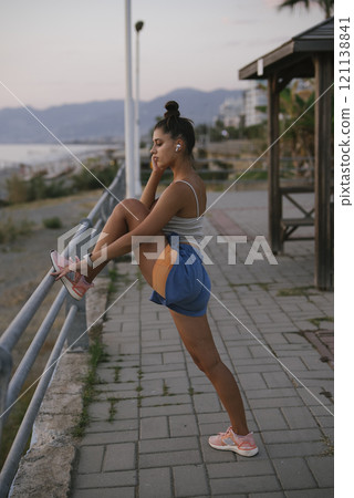 A young woman is actively and dynamically stretching her body by the beautiful seaside 121138841
