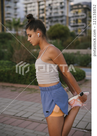 A Young Woman Engaging in Stretching Exercises Outdoors Before Commencing Her Workout A Young Woman Engaging in Stretching Exercises Outdoors Before Commencing Her Workout 121138852