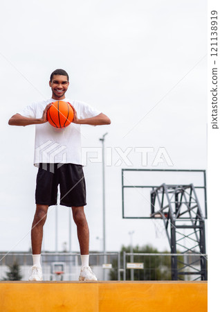 Tall handsome young man with a ball in hands looking confident Tall handsome young man with a ball in hands looking confident 121138919