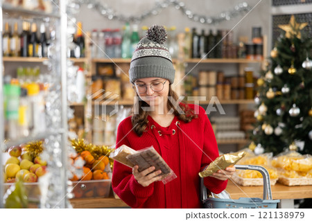 Teenage girl choosing and buying different candies and sweets for Christmas celebration 121138979