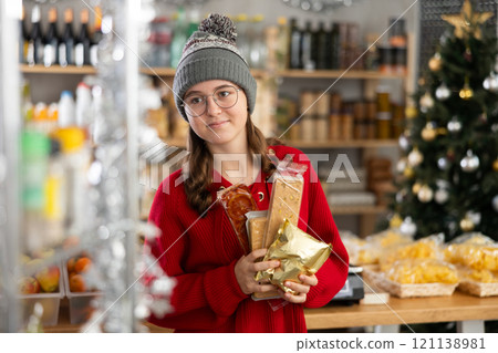 Happy teenage girl buys nougat in grocery section of supermarket for gifting and celebrating Christmas Happy teenage girl buys nougat in grocery section of supermarket for gifting and celebrating Christmas 121138981