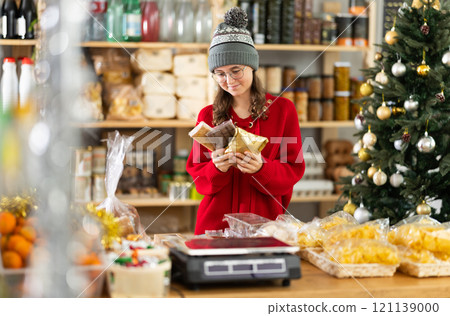 Teenage girl choosing and buying different candies and sweets for Christmas celebration 121139000