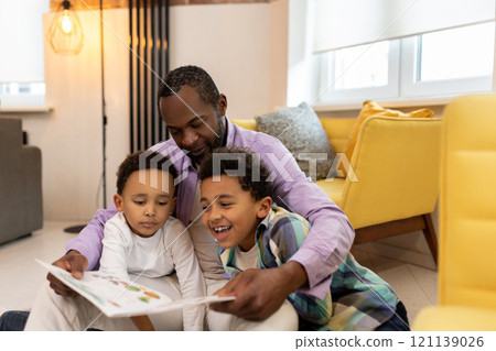 Happy family reading a book together and looking involved Happy family reading a book together and looking involved 121139026