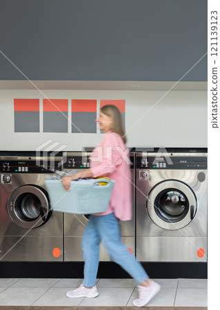 Mature woman in the laundry with a basket with clothes in hands 121139123