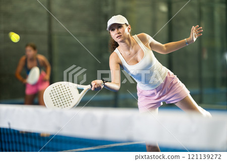 Woman playing padel on indoor court on summer day. Sport and active lifestyle concept 121139272