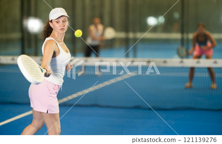 Adult woman playing tennis against man and woman Adult woman playing tennis against man and woman 121139276