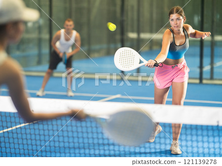 Young woman and man playing tennis against woman Young woman and man playing tennis against woman 121139278
