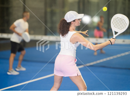 Adult woman and young man playing tennis against woman 121139293