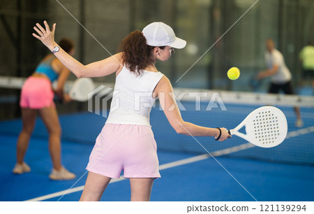 Woman playing padel on open court on summer day. Sport and active lifestyle concept Woman playing padel on open court on summer day. Sport and active lifestyle concept 121139294