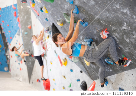 Young girl climbing on artificial rock wall in rock-climbing gym 121139310