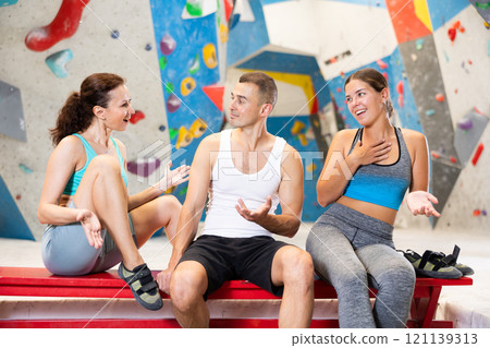 Young man and two women talking merrily sitting in climbing hangar 121139313