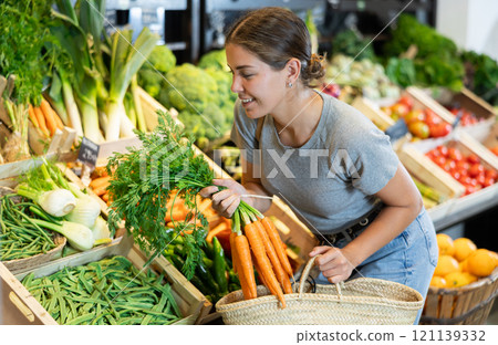 Young girl purchaser buying organic carrot in grocery store 121139332