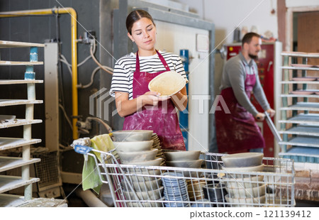 Young woman posing with ceramic dishes Young woman posing with ceramic dishes 121139412